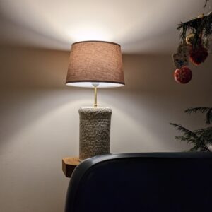 Une lampe en céramique posée sur un guéridon avec un fauteuil
